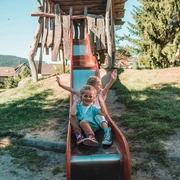 Zwei Kinder sitzen auf der Rutsche auf dem Spielplatz in Klosterreichenbach