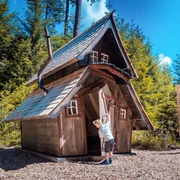 Ein kleiner Junge hat die Tür eines kleinen Holzhauses geöffnet und schaut hinein