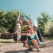 Zwei Kinder stehen neben einer Rutsche