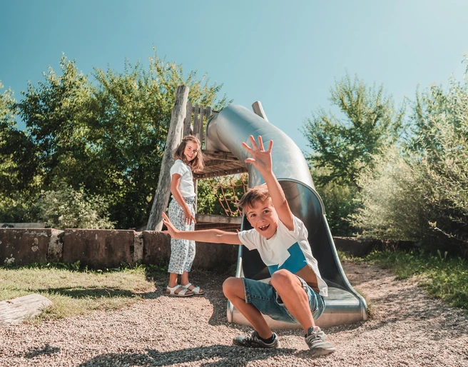 Zwei Kinder stehen neben einer Rutsche