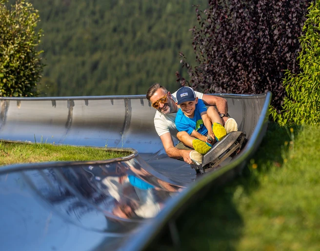 Mann und Junge auf der Sommerrodelbahn Mann und Junge auf der Sommerrodelbahn