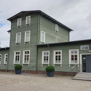 Historischer Bahnhof Rahden mit grüner Holzfassade und symmetrischen weißen Fenstern.