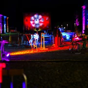 Außenbereich vom Zinkhütter Hof bei Dunkelheit. In der Mitte stehen verschiedene von Neonlicht angestrahlte Objekte.
