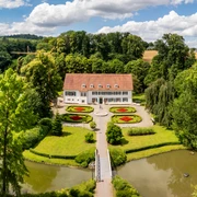 Kurpark Bad Holzhausen Luftaufnahme des Kurparks Bad Holzhausen mit symmetrischen Blumenbeeten und einem historischen Gebäude.