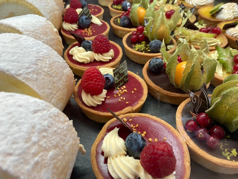 Sweet Cologne Eine köstliche Auswahl bunter Törtchen und süßer Gebäcke, verziert mit frischen Beeren.A delicious selection of colorful tarts and sweet pastries, decorated with fresh berries.
