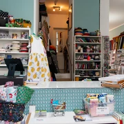Toddlin Town Kinderbekleidung – Shopping in Leipzig In dem Kinderbekleidungsgeschäft Toddlin Town stapeln sich viele bunte Stoffmuster – Handarbeit, Kreativität, Kindermode