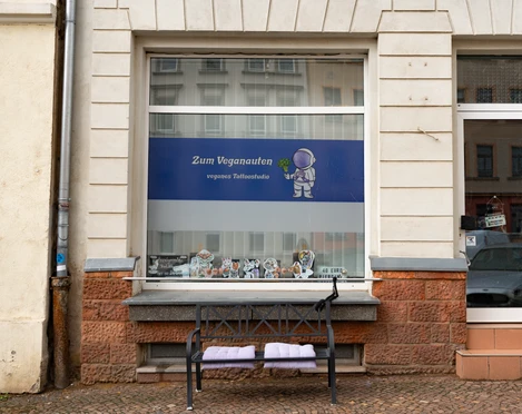 Zum Veganauten Tattoostudio Außenansicht Das Logo des Tattoostudios ist ein kleiner Astronaut, der einen Brokkoli hält