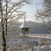 Rechte BSKT, Cornelia Rülke.JPG Verschneite Brücke durch einen Winterwald mit Aussichtsturm, umgeben von schneebedeckten Bäumen.
