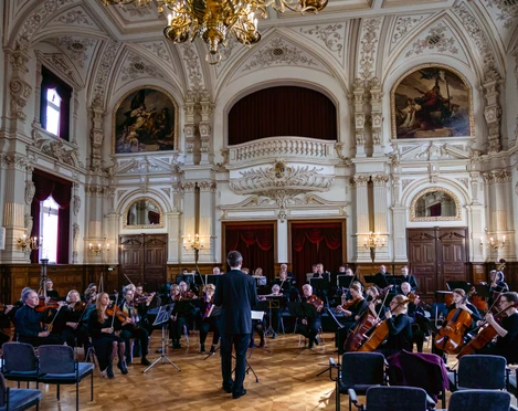 Schlossorchester Oldenburg Opulenter Saal mit dekorativen Deckenverzierungen, in dem Schlossorchester Oldenburg probt.