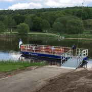Personenfähre in Wehrden Personenfähre "Weser-Waler" dockt auf ruhigem Fluss an, umgeben von üppigem Grün und Wanderwegen.