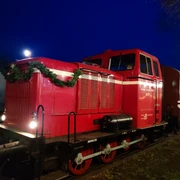 Rote Diesellokomotive der Museumseisenbahn Nikolaus, abends, mit Tannengirlande dekoriert.