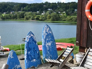 Stühle und ehemalige Surfbretter im Vordergrund und Edersee im Hintergrunf