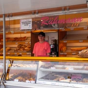 Mein Bäcker Rühmann Verkaufswagen mit Bäckerei-Artikeln Eine Verkäuferin steht darin.