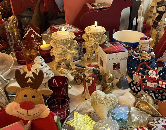 Foto 1 ArtD_ Weihnachtsecke.jpeg Verschiedene Weihnachtsdekorationen, darunter Engelsfiguren, ein rotes Rentier und festliche Kerzen.