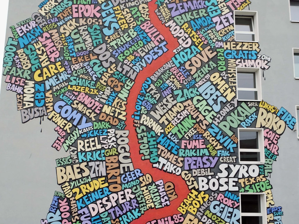 Mural Eine bunte Wandgemälde-Collage in Köln: Wörter als Kunst formen eine regionale Karte.A colorful mural collage in Cologne: words as art form a regional map.