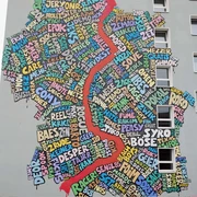 Mural Eine bunte Wandgemälde-Collage in Köln: Wörter als Kunst formen eine regionale Karte.A colorful mural collage in Cologne: words as art form a regional map.