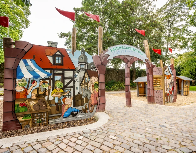 Höxter-Spielplatz Welt des Mittelalters-Teutoburger-Wald-Stadt Höxter-D-Ketz-175.jpg Spielplatzwand mit historischer Marktszene und Gucklöchern Playground wall with historical market scene and peepholes