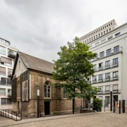 Kaune Contemporary Gallery Eine historische Kapelle, umgeben von moderner Architektur im Herzen einer Stadt.A historic chapel surrounded by modern architecture in the heart of a city.