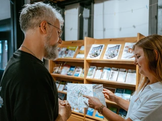 Tourist-Information Mitarbeiterin der Tourist-Information berät einen Kunden.