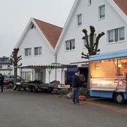 Wochenmarkt Stemwede Stände auf dem Wochenmarkt Stemwede, Anbieter in blauen Verkaufswagen, Besucher bummeln entspannt.