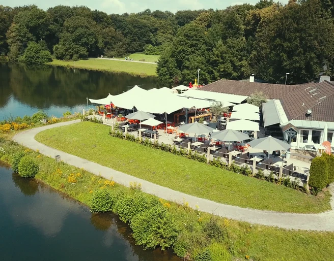 HAUS AM SEE Haus am See von oben mit Terrasse, bestückt mit aufgespannten SonnenschirmenHouse on the lake from above with terrace, equipped with stretched parasols