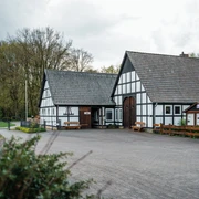 Museumshof Rahden  Historische Fachwerkgebäude umgeben von Bäumen, mit Informationstafel und einladendem Vorplatz.