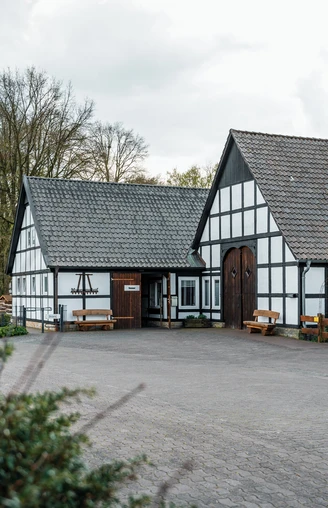 Museumshof Rahden  Historische Fachwerkgebäude umgeben von Bäumen, mit Informationstafel und einladendem Vorplatz.