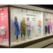 BSPNGN-FASHIONROOM.jpg Nachtaufnahme eines Schaufensters mit modischer Bekleidung und farbigen Wanddisplays.