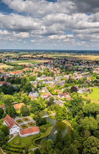 Preußisch-Oldendorf-Kurpark Bad Holzhausen Luftaufnahme des Kurparks Bad Holzhausen mit grünen Wiesen, einem Teich und umliegenden Gebäuden.