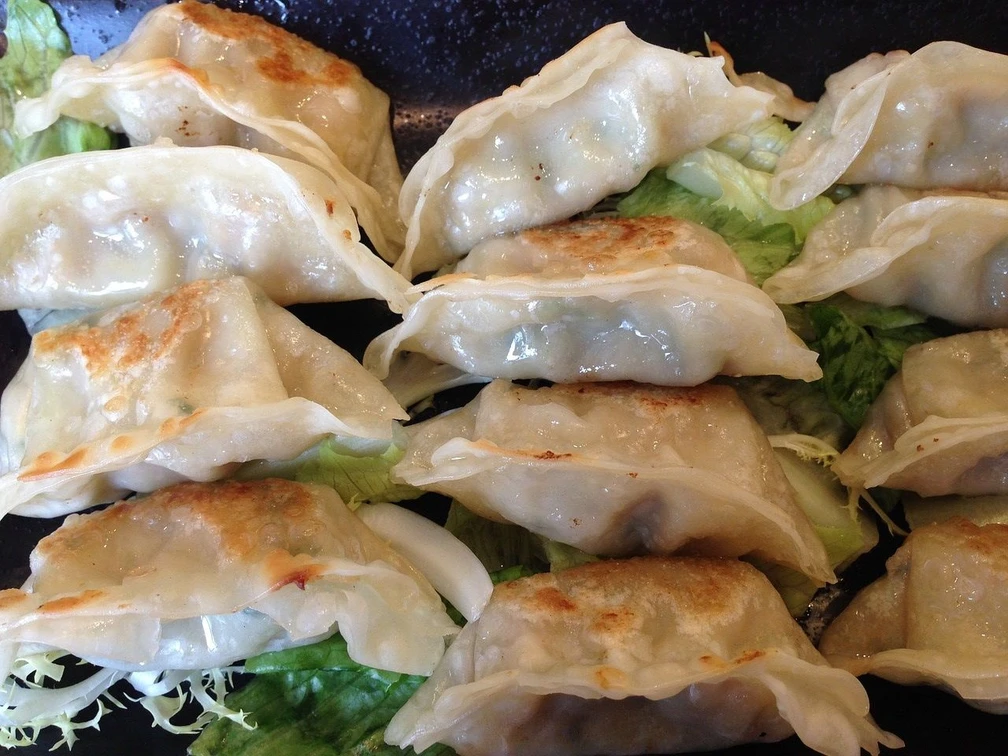Dumplings liegen nebeneinander auf Salatblättern.