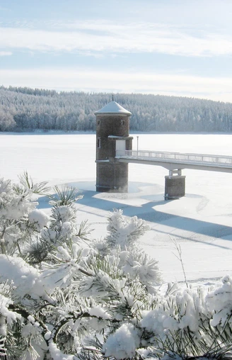 Verschneite Wasserfläche der Talsperre Cranzahl mit Turm