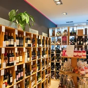 Barrique: Weinregal In einem Geschäft sind hohe Regale an den Wänden, die mit vielen verschiedenen Weinflaschen gefüllt sind.