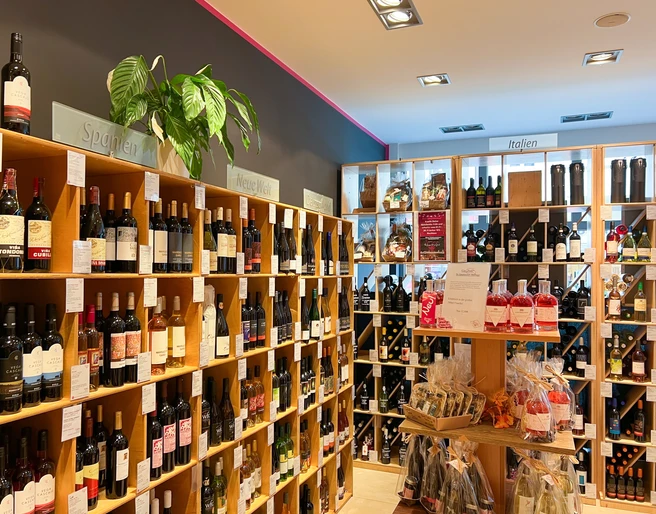 Barrique: Weinregal In einem Geschäft sind hohe Regale an den Wänden, die mit vielen verschiedenen Weinflaschen gefüllt sind.