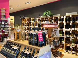 Barrique In einem Geschäft sind hohe Regale an den Wänden, die mit vielen verschiedenen Weinflaschen gefüllt sind.