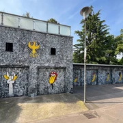 Spraygrammtechnik Bananensprayer Winckelmannstraße 11 2 Graffiti an einer grauen Fassade: Bananensymbole und Rolling-Stones-Mund illustrieren die Wand.Graffiti on a gray façade: banana symbols and Rolling Stones mouth illustrate the wall.