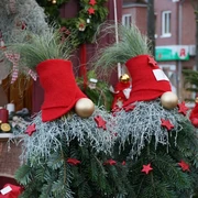 Weihnachtswichtel Weihnachtlich geschmückte Tannenzweige mit roten Zipfelmützen und goldenen Kugeln auf dem Markt.