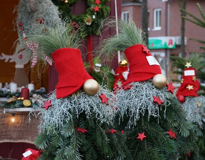 Weihnachtswichtel Weihnachtlich geschmückte Tannenzweige mit roten Zipfelmützen und goldenen Kugeln auf dem Markt.