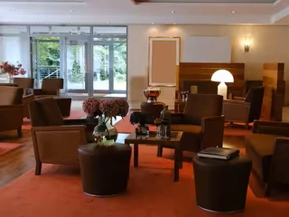 Bar im Ramada by Wyndham Düsseldorf Ratingen Elegante Hotelbar mit Ledersesseln und Tischlampen, durch Fenster Blick ins Grüne.