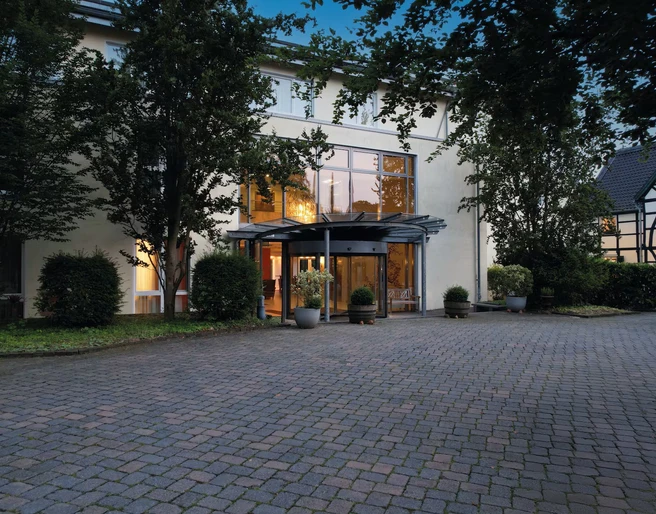 Eingang ins Ramada by Wyndham Düsseldorf Ratingen Der Eingang des Ramada by Wyndham Hotels in Düsseldorf Ratingen mit Glasdach und gepflastertem Vorplatz.