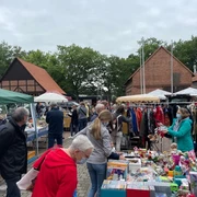Flohmarkt-Scheunenviertel-SieversCopy Menschen stöbern auf einem belebten Flohmarkt mit offenen Ständen, umgeben von Fachwerkgebäuden.