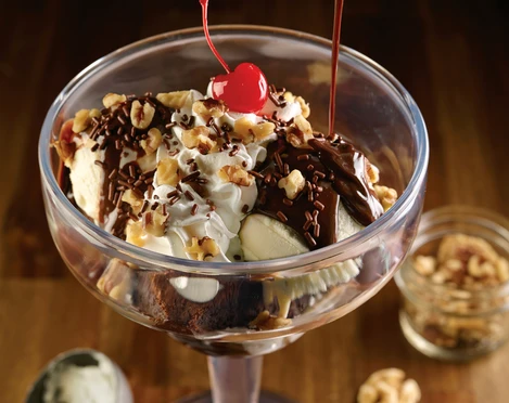 HRC Hot Fudge Brownie 6.jpeg Dessert im Cocktailglas, Schokosoße wird aus einer kleinen Sauciere auf das Dessert gegossenDessert in a cocktail glass, chocolate sauce is poured onto the dessert from a small sauce boat