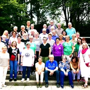 P1110863.JPG Eine Gruppe von 33 Menschen sitzt auf Treppenstufen, umgeben von grünen Bäumen.
