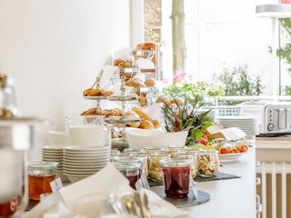 Frühstück Frühstücksbuffet mit kleinen Müsligläsern und Etageren mit GebäckBreakfast buffet with small cereal jars and trays of pastries