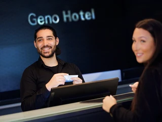 Rezeption Rezeption: ein Mann hilf einer Frau beim Check-In ProzessReception: a man helps a woman with the check-in process