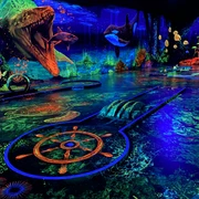 Schwarzlichtgolf.jpeg Faszinierendes Schwarzlicht-Minigolf mit lebhaften Unterwasserszenen und leuchtenden Farben.
