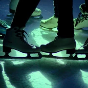 Eislaufdisco in Aachen Nahaufnahme von mehreren Schlittschuhen auf beleuchteter Eisfläche.