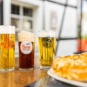 Zollhäuschen Kneipe Drei köstliche, frisch gezapfte Biere in unterschiedlich hohen, schlanken Gläsern vor Fachwerkhaus.