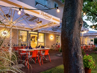 Außengastronomie im Kristallhotel FETTEHENNE Außengastronomie des Kristallhotels FETTEHENNE in Leverkusen mit beleuchteten Tischen unter Bäumen.