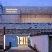 Gedenkstätte-JVA-WF-Eingang.jpg Gedenkstätte Wolfenbüttel, Steingebäude mit Stacheldraht, offener Eingang