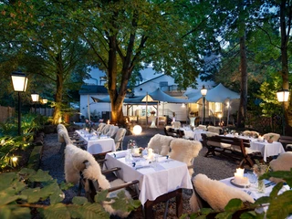 Biergarten im Gästehaus FETTE HENNE in Erkrath Stimmungsvolle Atmosphäre im Biergarten mit beleuchteten Tischen, Kerzen und umringt von Bäumen.